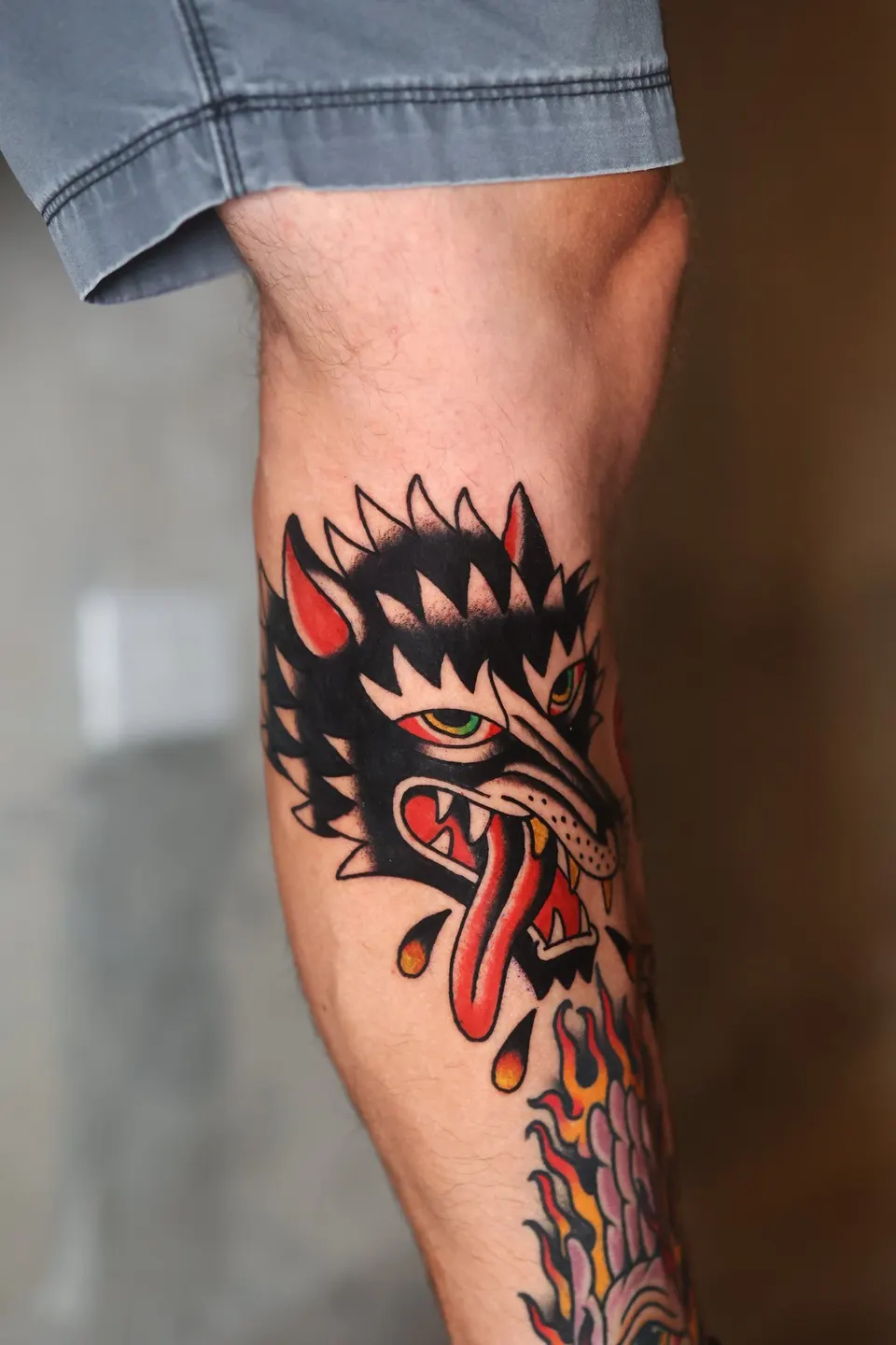 Black wolf head with red tongue, American traditional tattoo by Ulises Malavé
