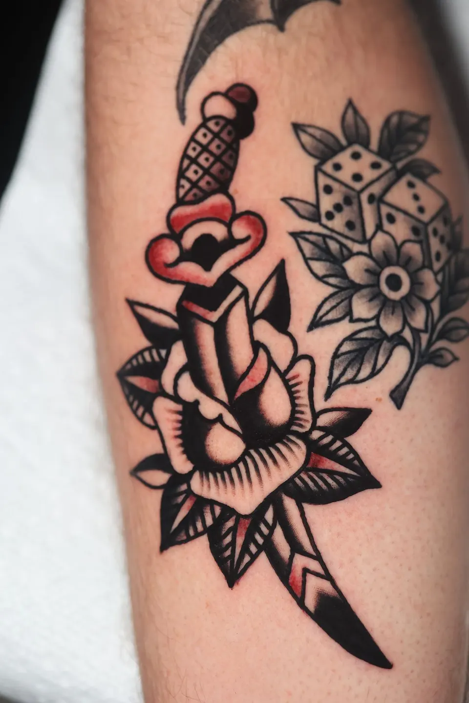 Dagger through rose with dice and bat, American traditional tattoo by Ulises Malavé