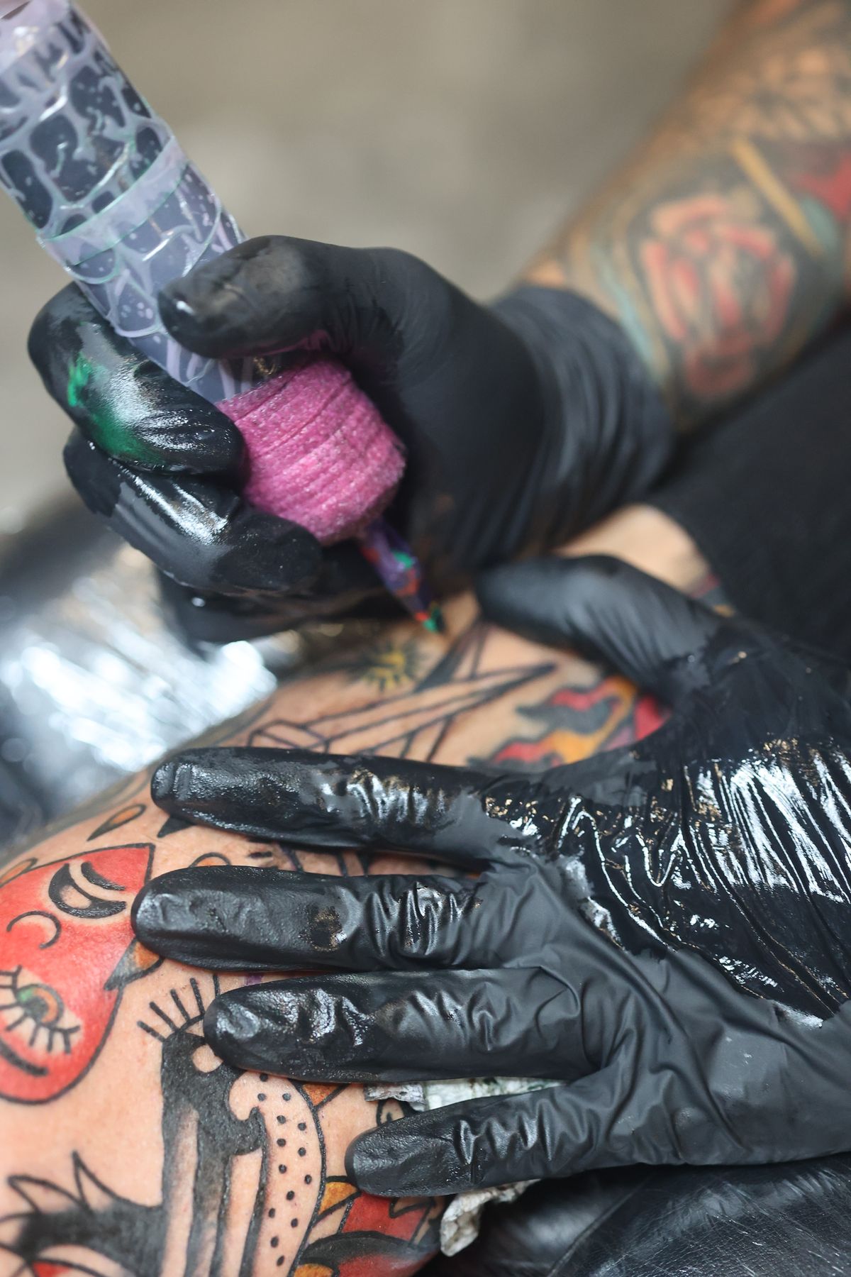 Close-up of Ulises tattooing, machine in gloved hands