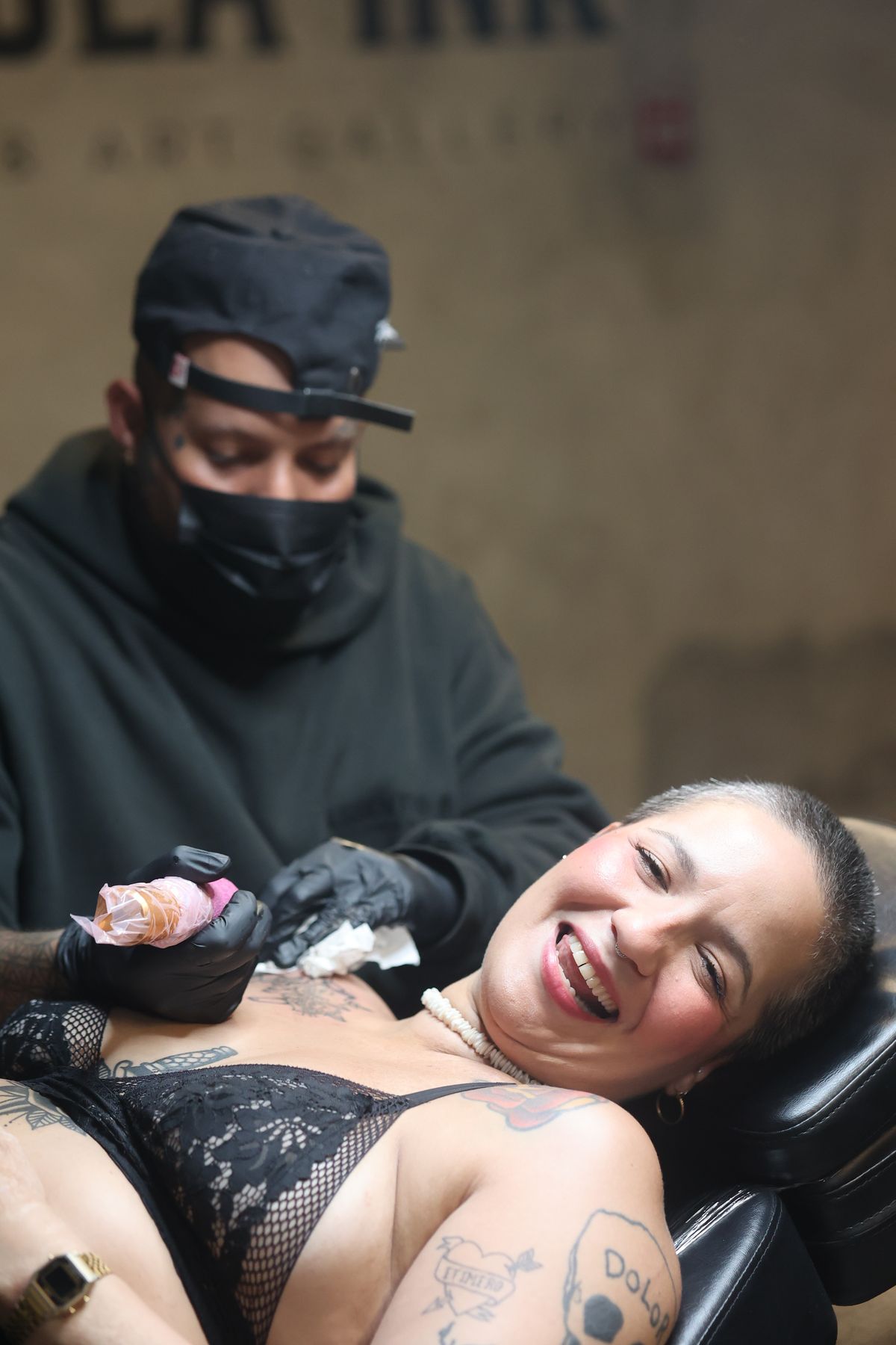 A client laughs mid-session while Ulises Malavé tattoos her at Pangea Ink